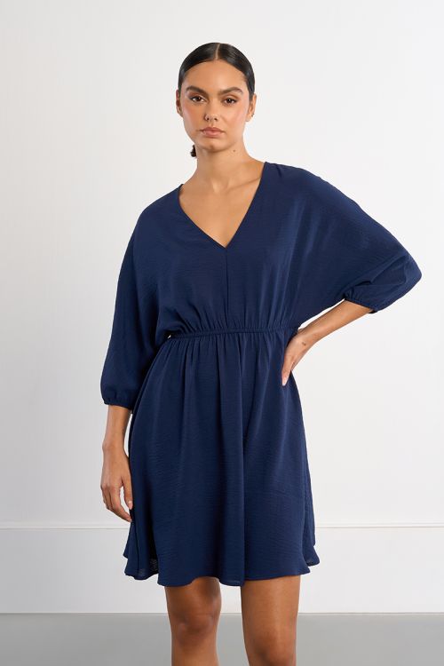 Vestido corto, de manga larga, detalle pliegues.